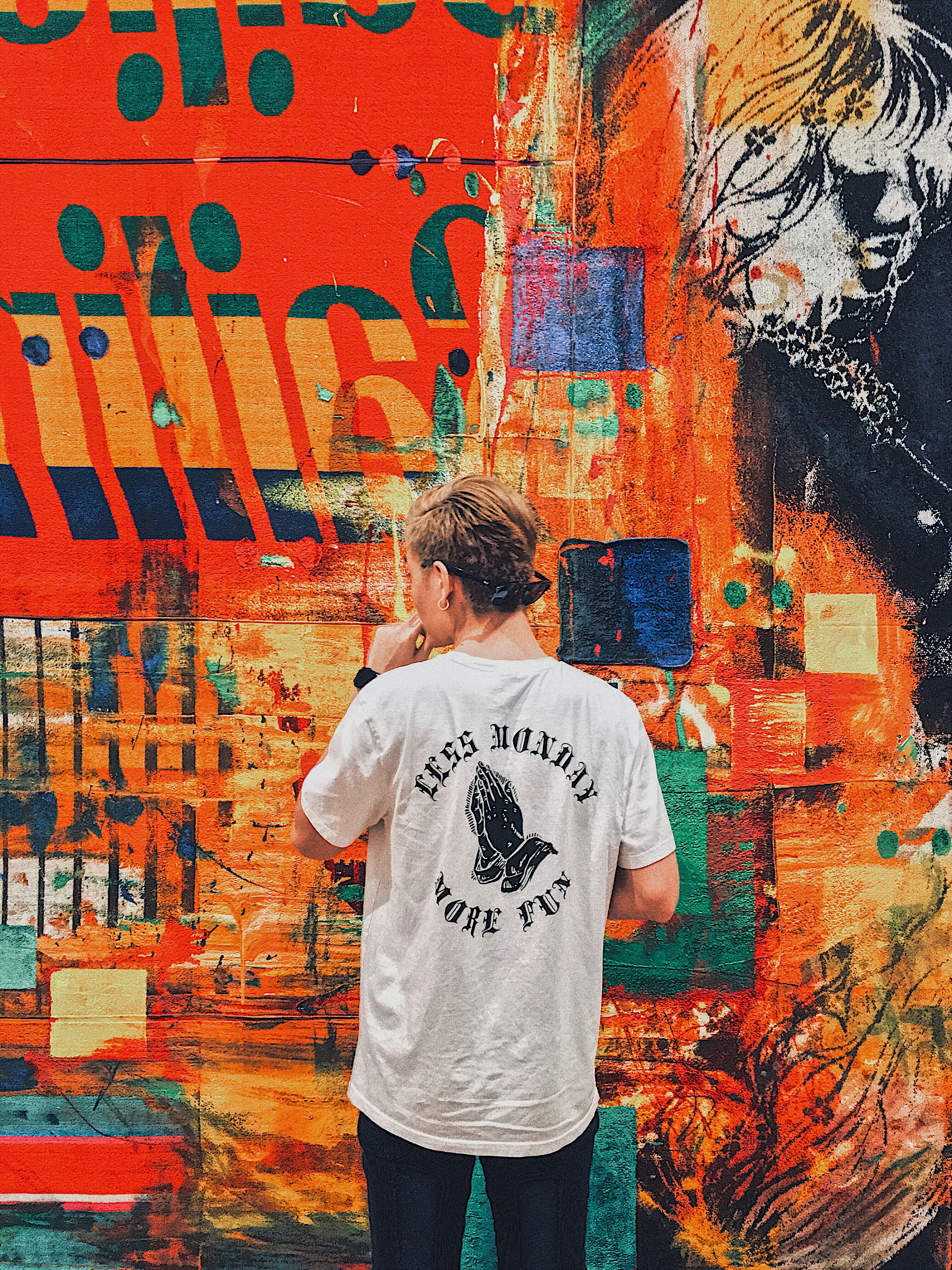 man holding his chin facing multicolored painted wall